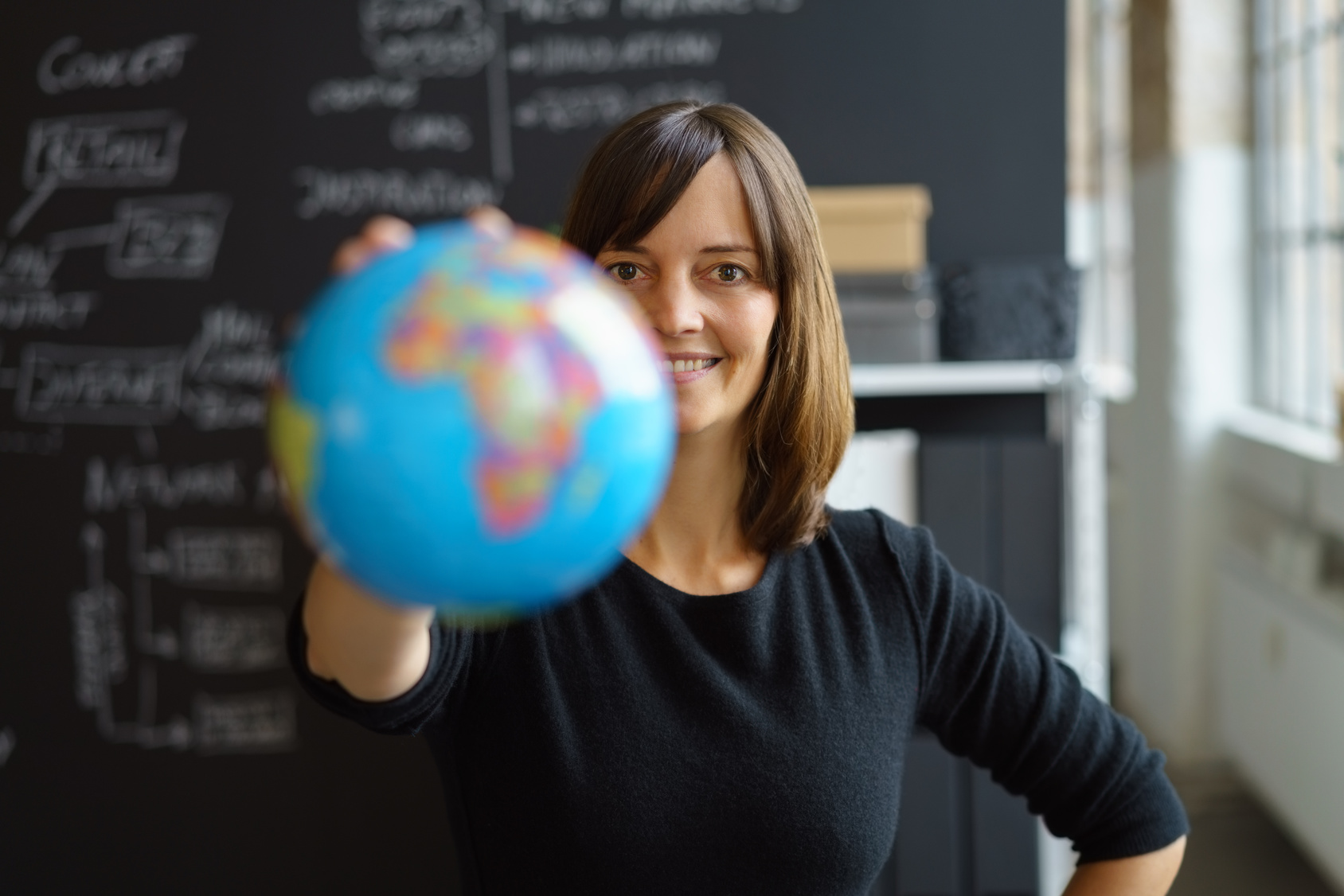 woman in a classroom holding a globe