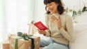 Woman reading Christmas card, surrounded by presents and Christmas decorations
