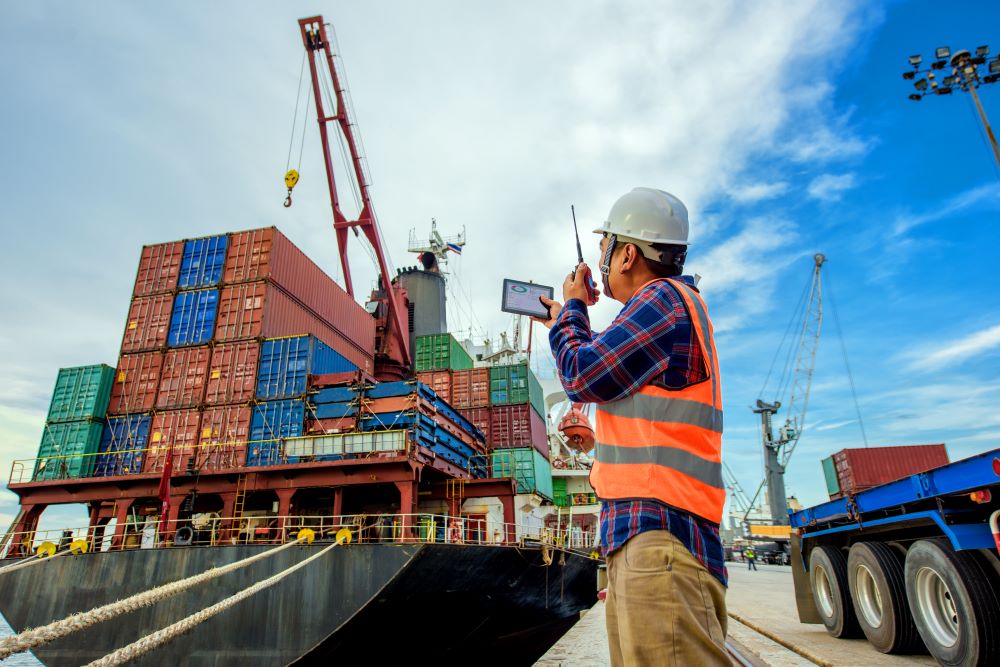 Worker guiding freight crates onto ship