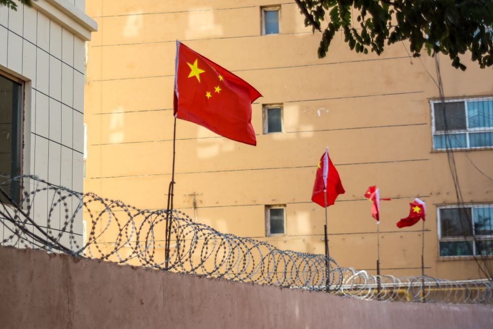 Chinese flags over prison wall with barbed wire