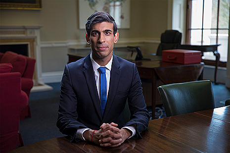 Rishi Sunak sat at table in office with hands clasped in front of him