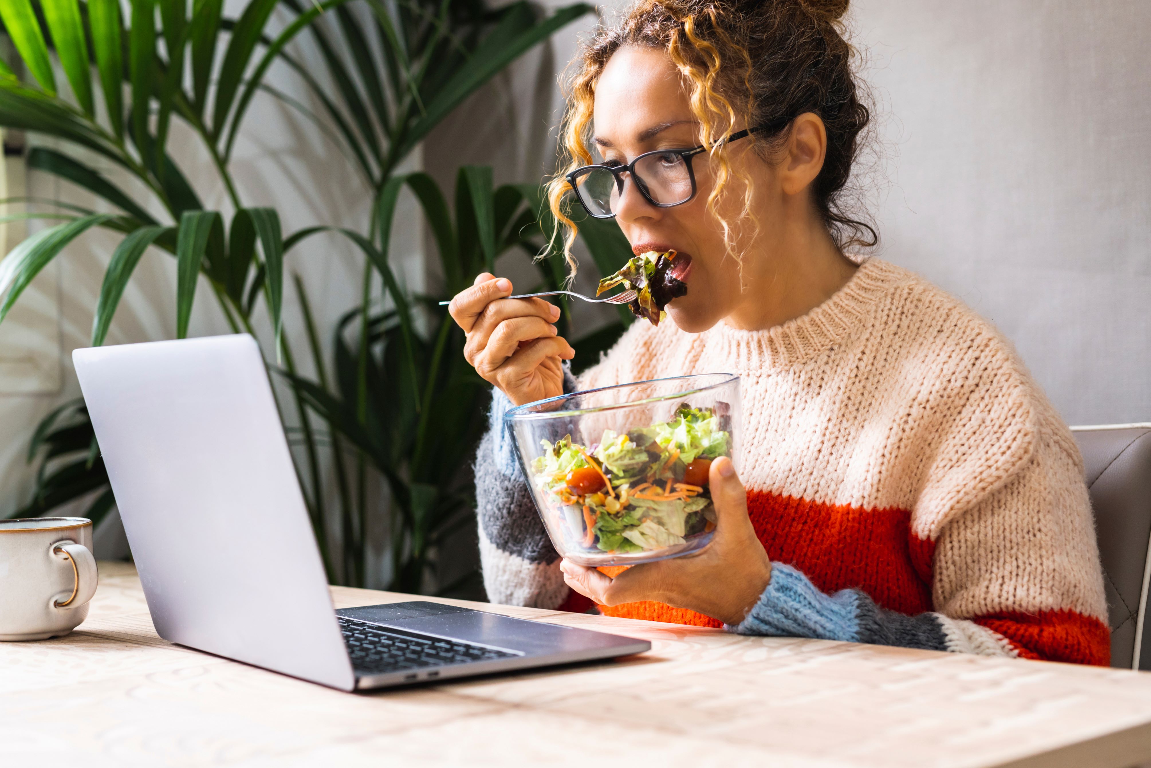 Woman eating lunch in front of a laptop