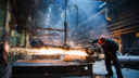 Man in factory cuts sheet of steel, sparks fly