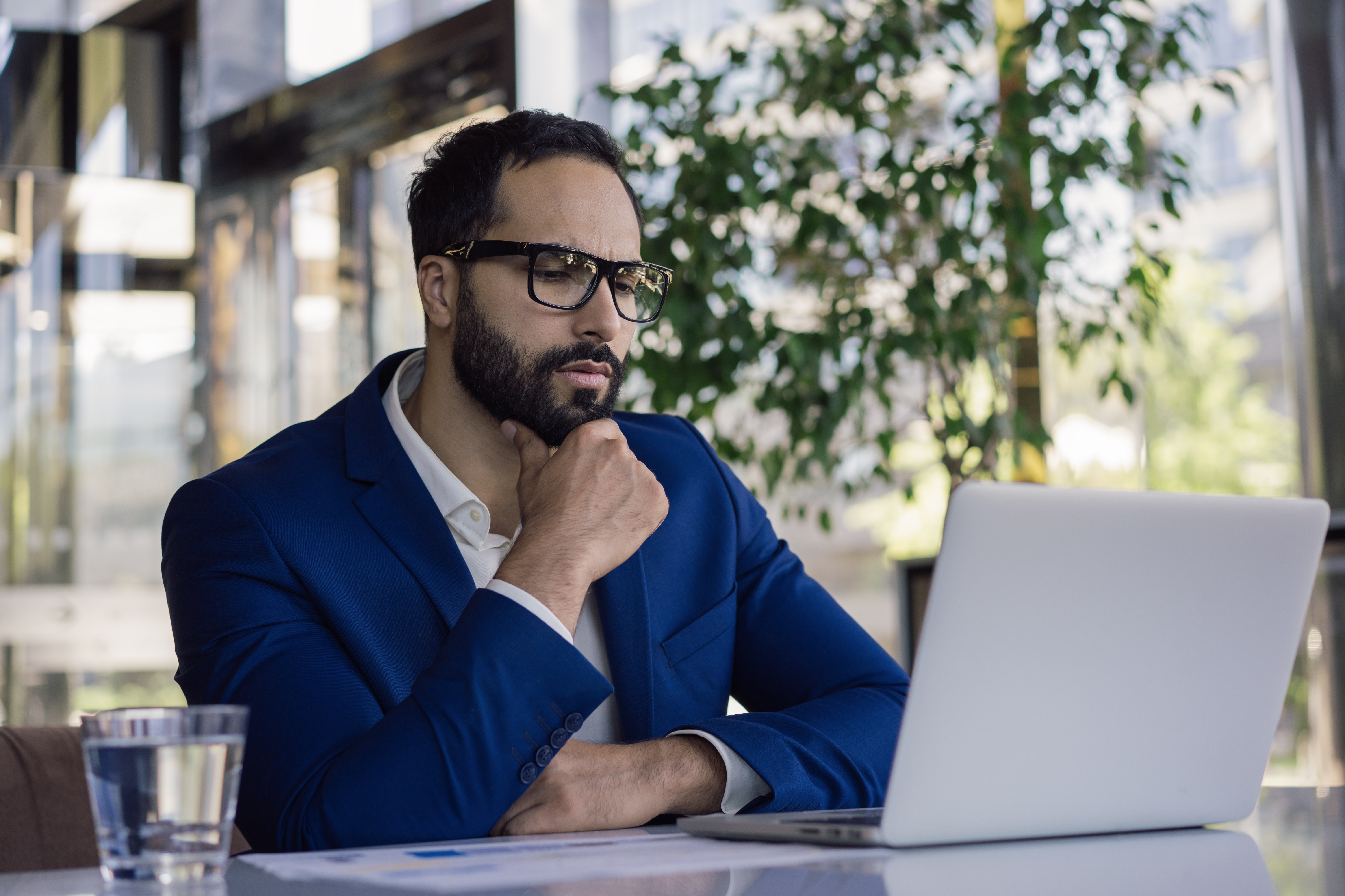 Trader studying documents on laptop at desk 